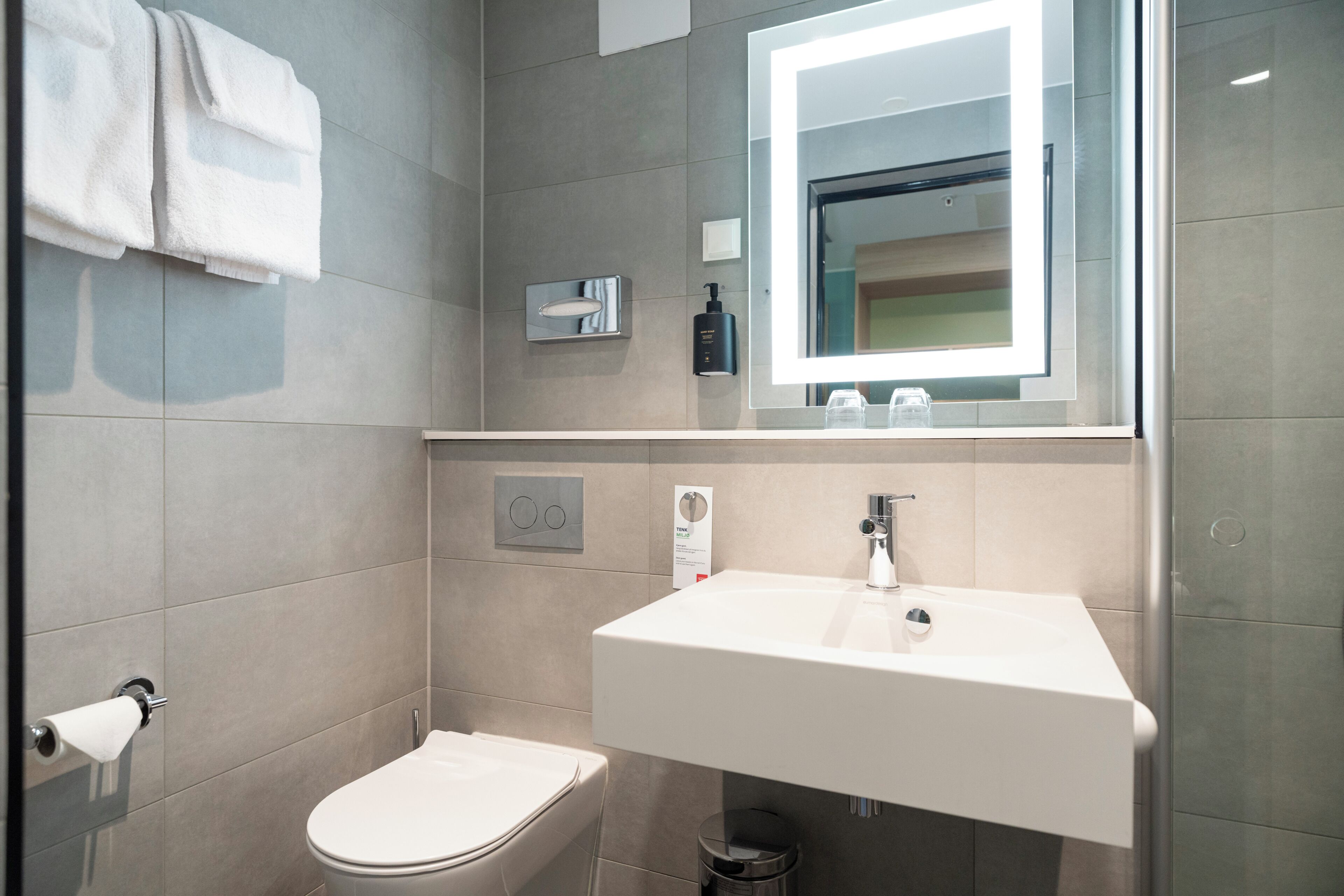 A modern bathroom with a toilet, sink, and mirror.