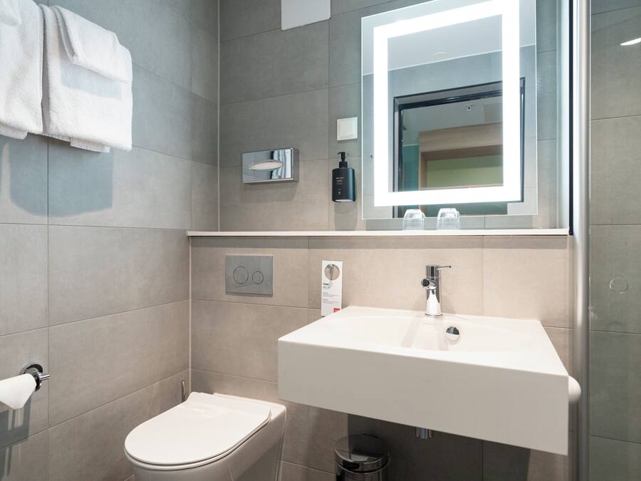 A modern bathroom with a toilet, sink, and mirror.