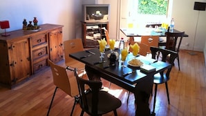 Un comedor con una mesa de madera, sillas y un televisor al fondo.