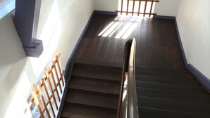 Una escalera de madera con barandilla metálica, que conduce a una plataforma con pasamanos de madera.