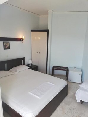 Une chambre à coucher avec un grand lit, une table de chevet avec une lampe, une petite table et une armoire.