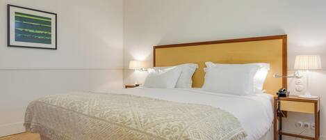 A neatly made bed with a patterned throw, a wooden headboard, and bedside lamps.