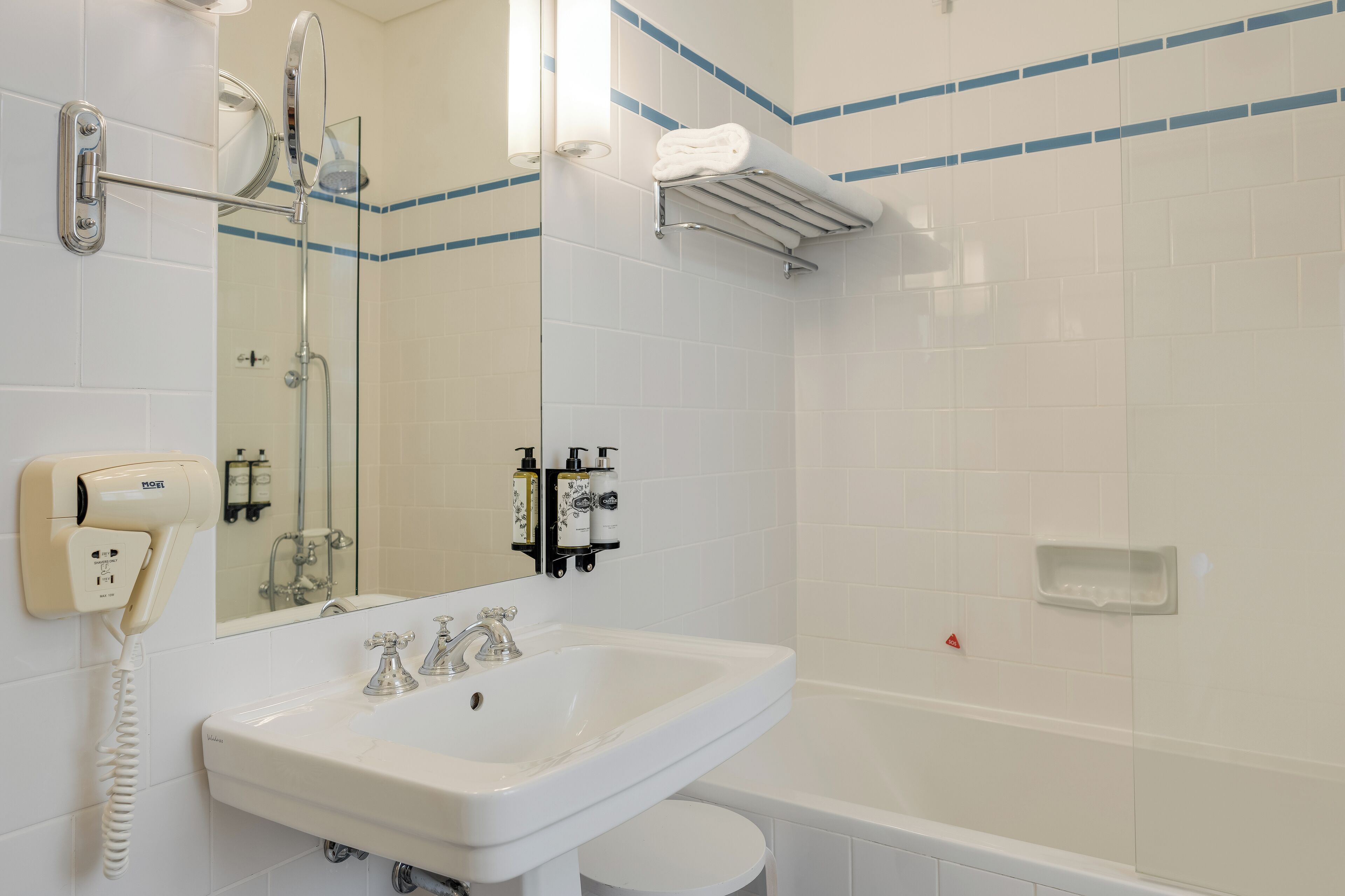 A bathroom with a white sink, mirror, and glass shower enclosure.