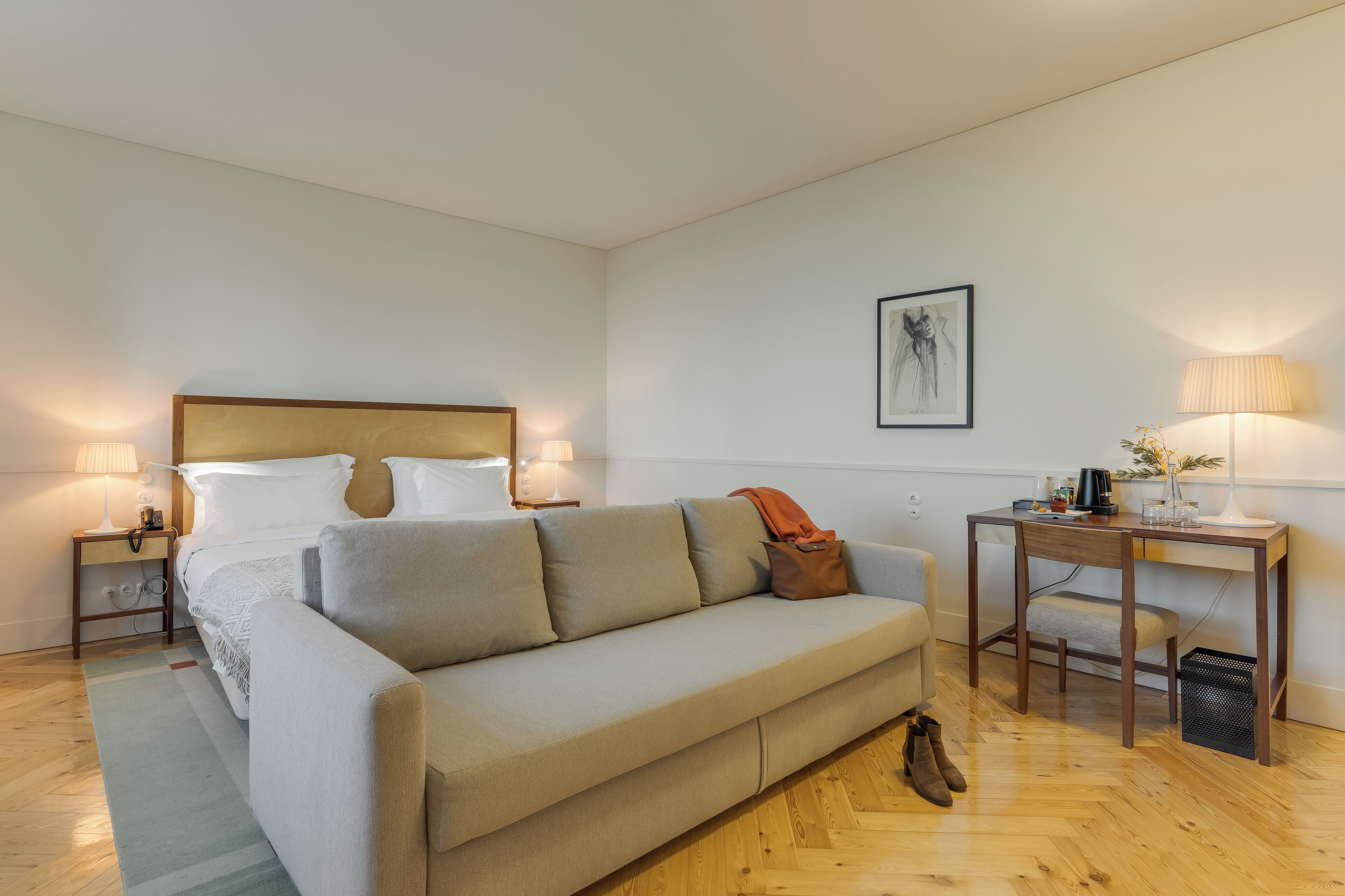 A bedroom with a bed, a sofa, a desk, and a chair.