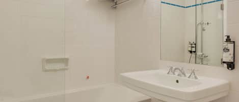 A bathroom with a white sink, a glass shower enclosure, and a towel rack.