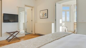 Une chambre à coucher avec un lit, une télévision, un tableau et une vue sur l’extérieur.
