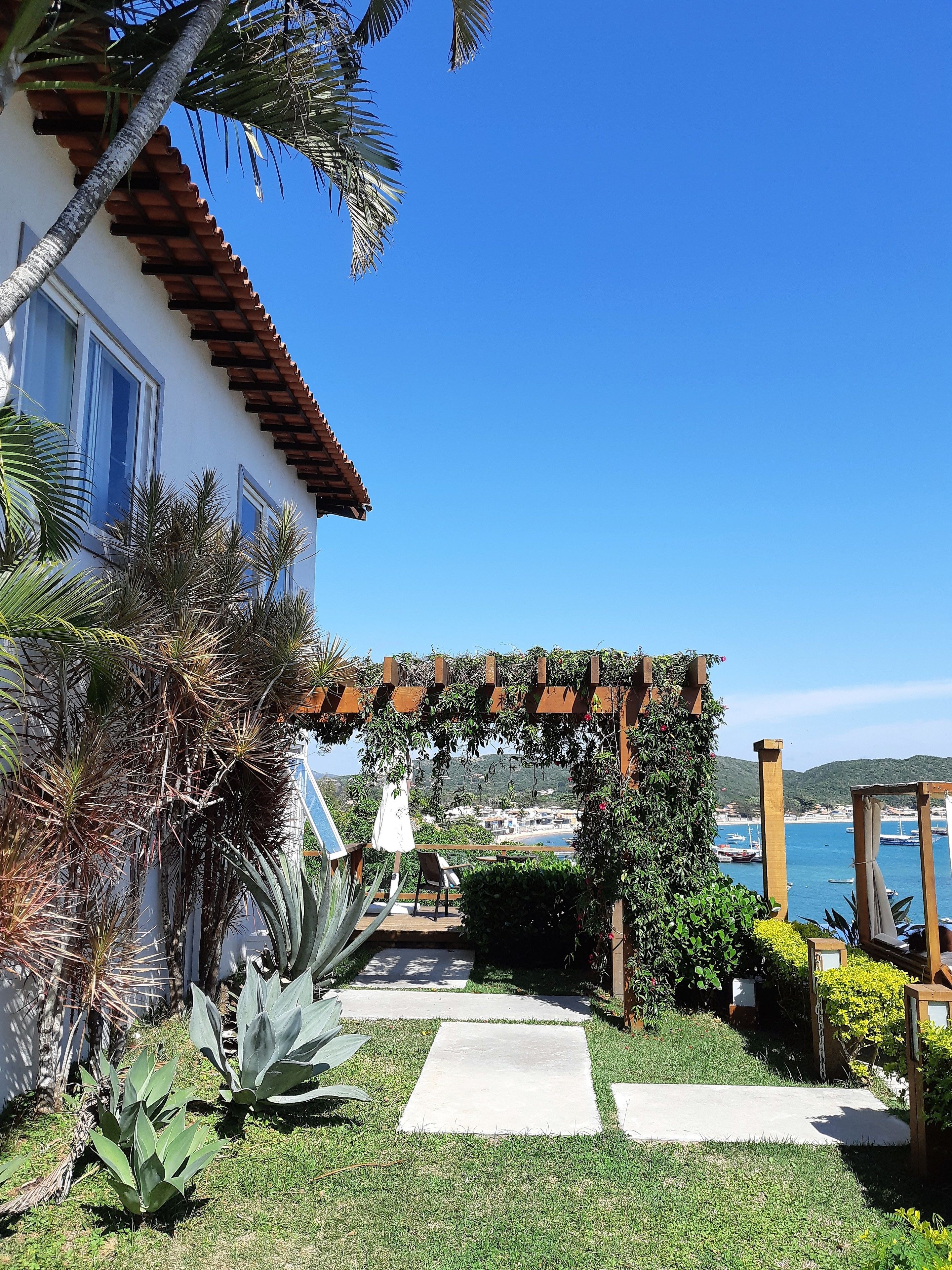 A house with a patio, a pergola, and a view of a coastal town.