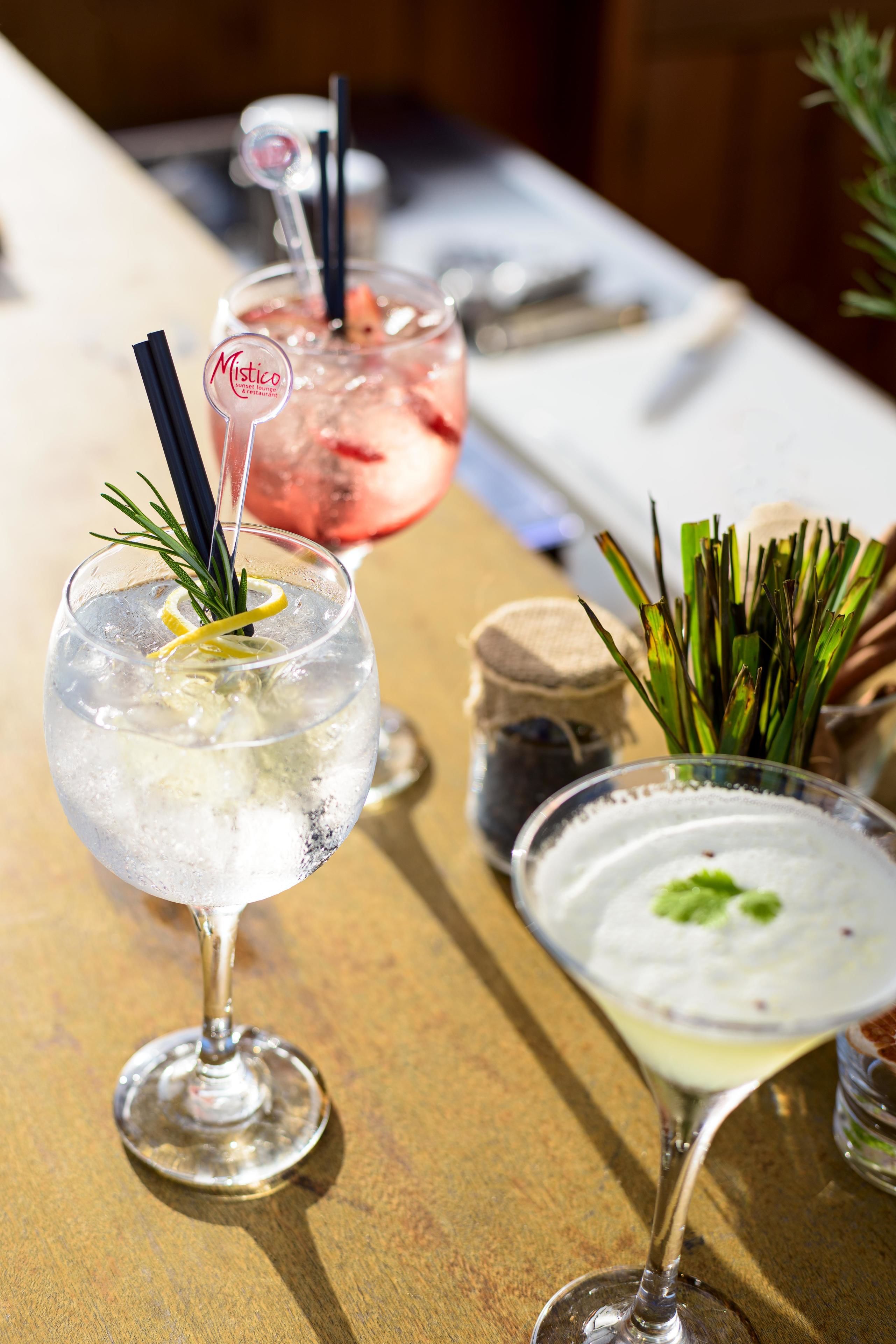 Three cocktails on a wooden table with a white cloth.