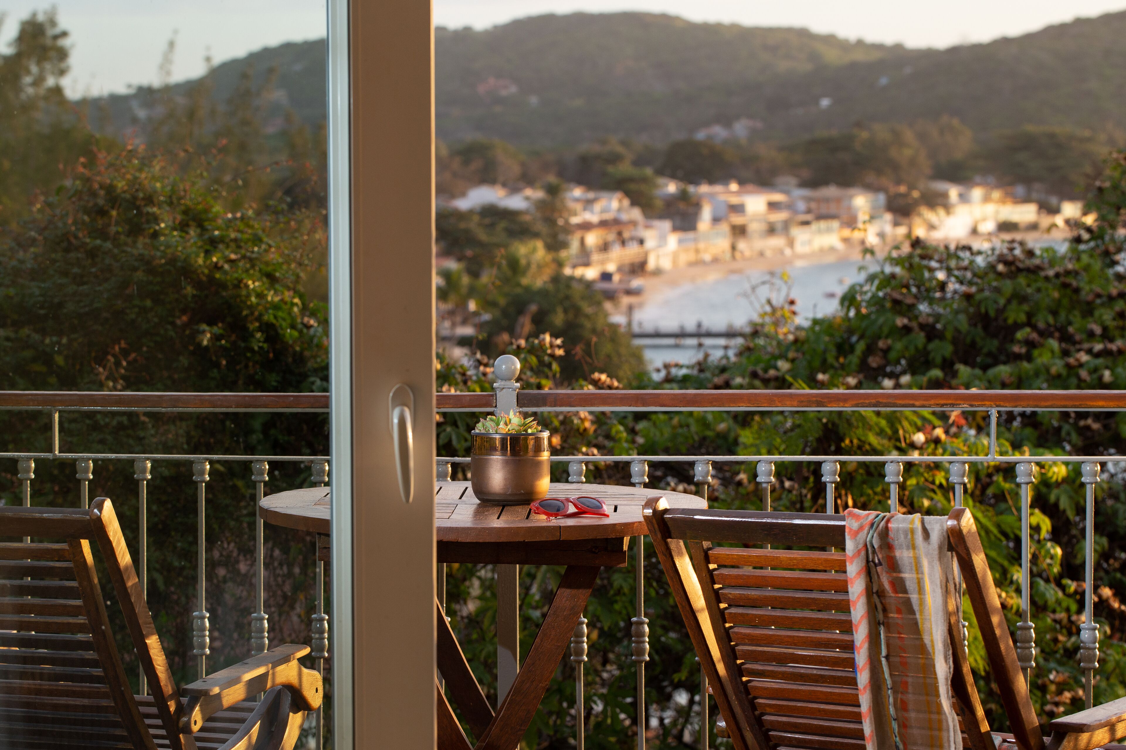 A balcony with a table, chairs, and a view of a coastal town.