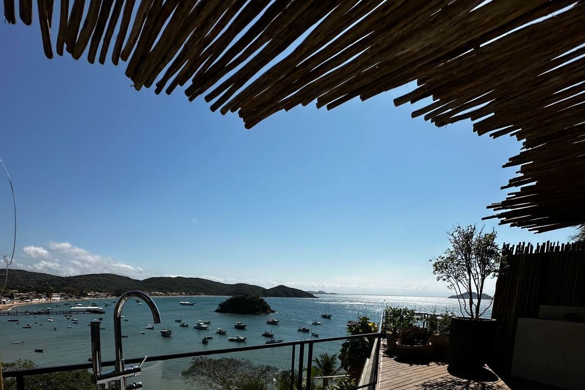 Una bañera blanca en una terraza de madera, con vistas a barcos y una isla distante.