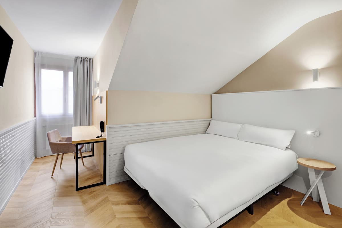 A bedroom with a bed, a desk, and a chair.