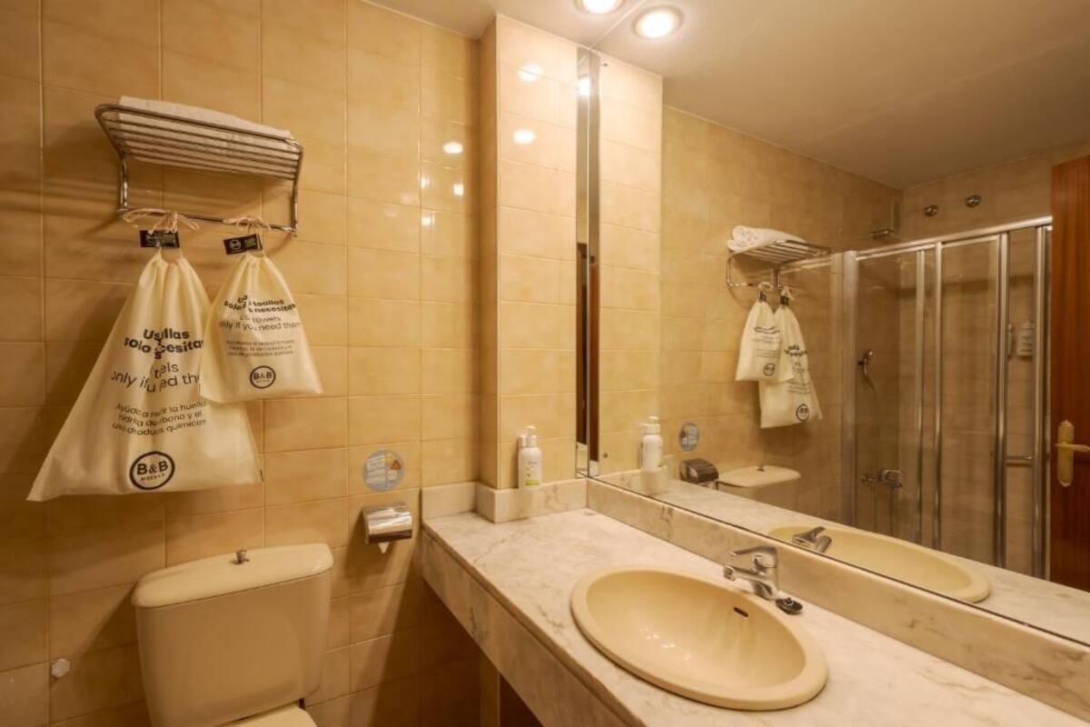 Een badkamer met toilet, wastafel, spiegel en douche.