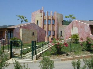 A building with a unique architectural design, featuring a central tower and multiple windows. - Il Borgo di Porto Corallo (Villaputzu)