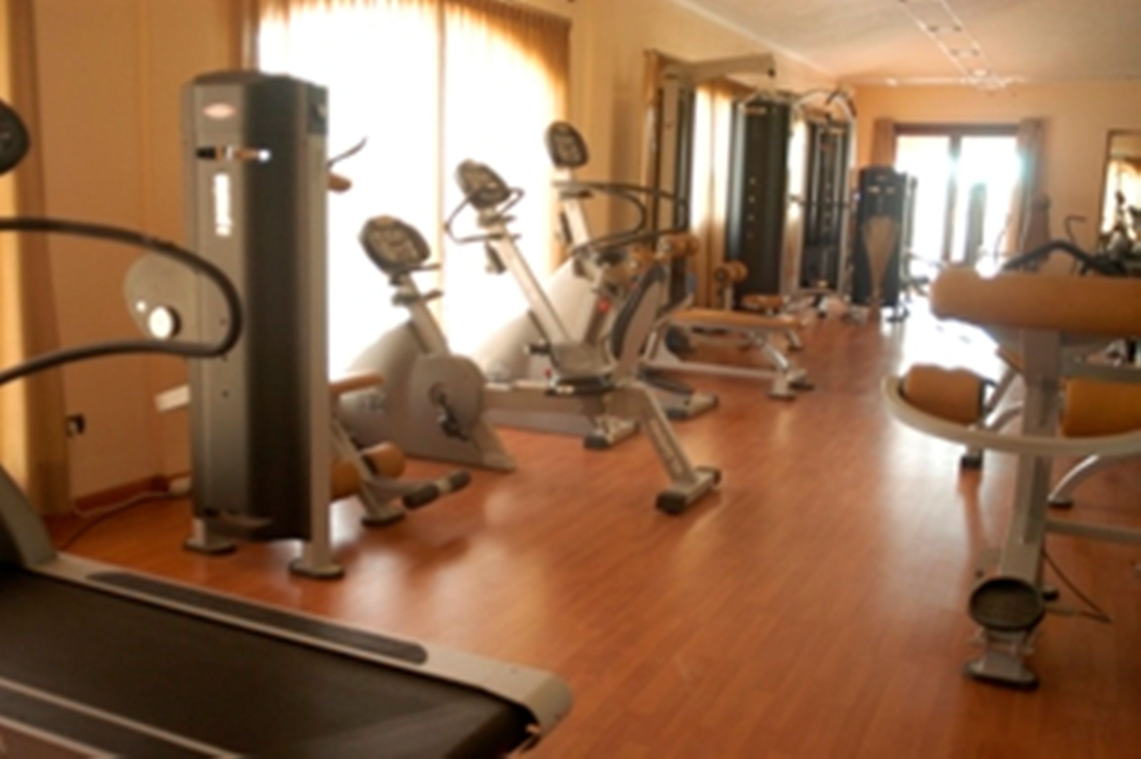 A gym with various exercise equipment including treadmills, stationary bikes, and weight machines.