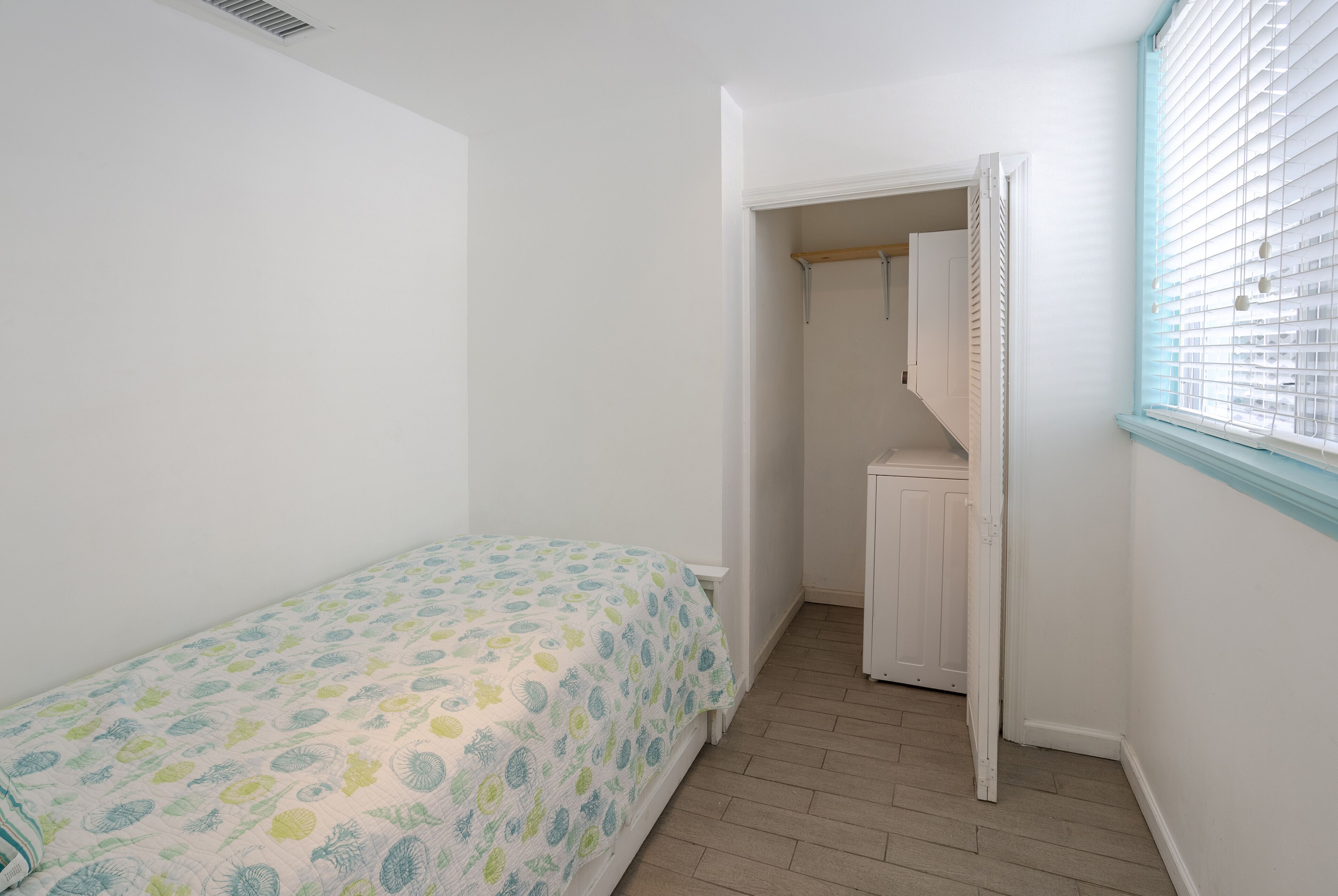 A bedroom with a bed, a closet, and a window.