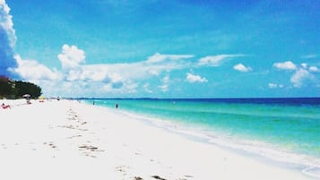 Pantai di sekitar, pasir putih, payung pantai, dan handuk pantai