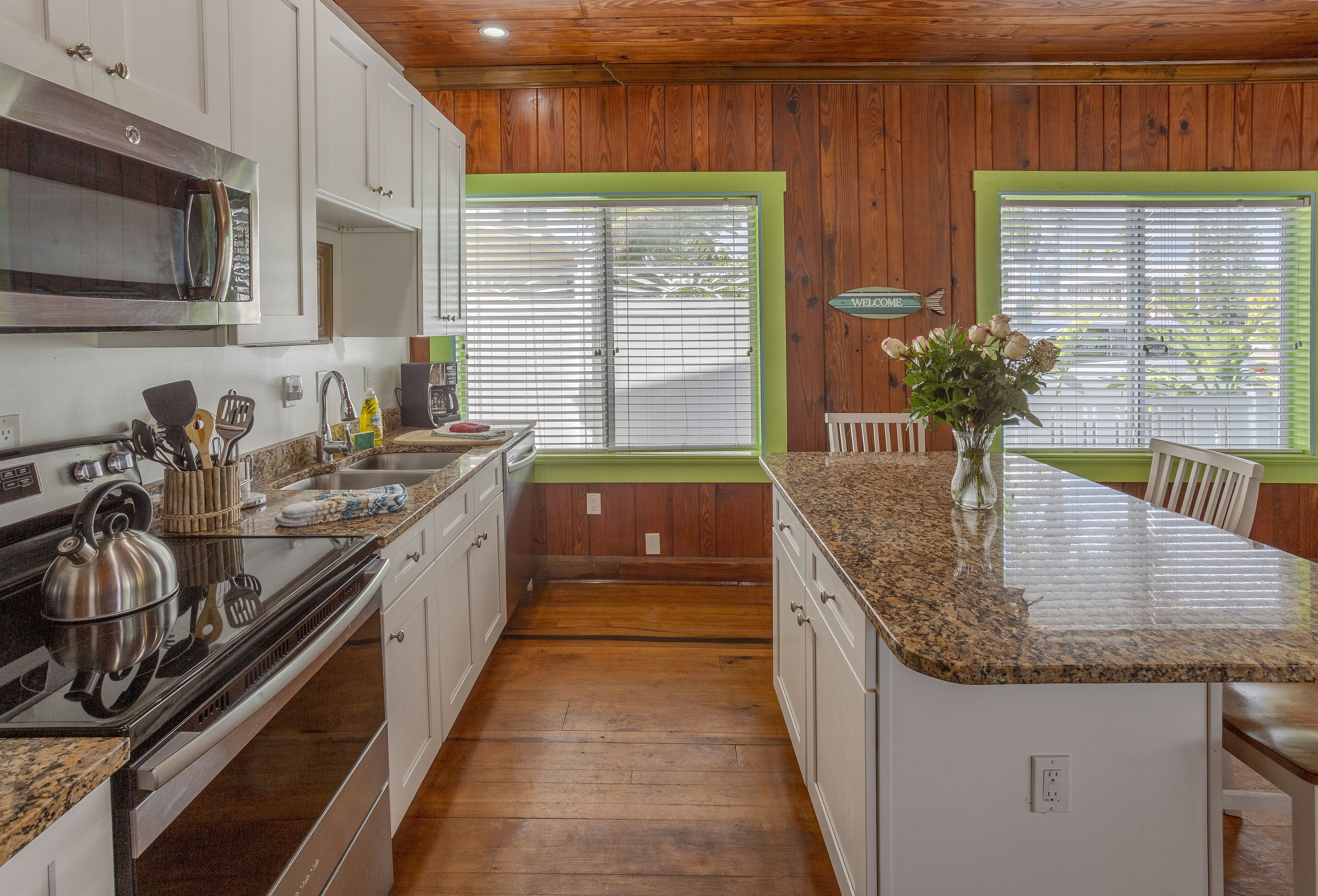 A kitchen with wooden paneling, a granite countertop, and a central island.