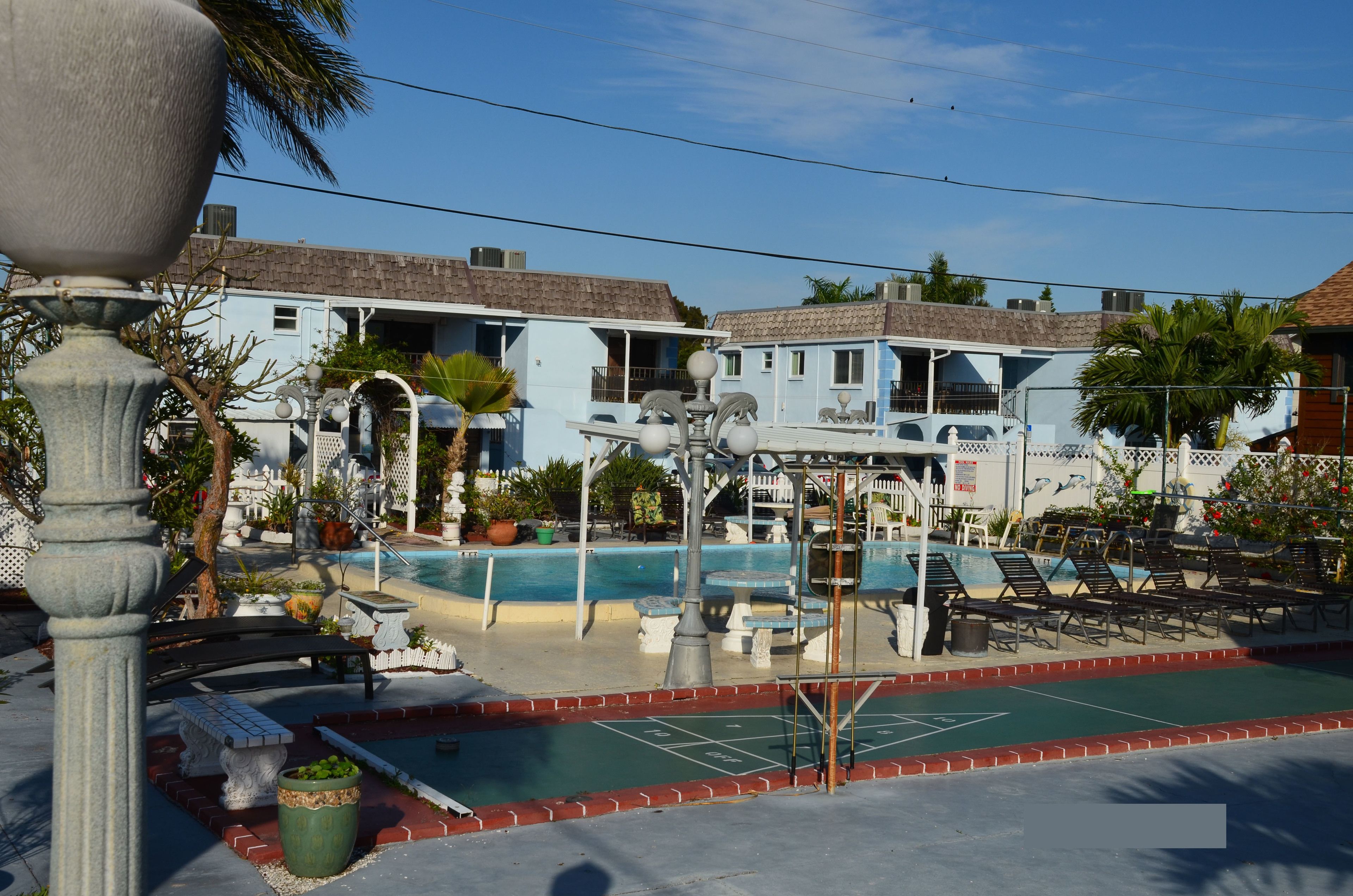 A pool area with lounge chairs, a water feature, and a building with a tiled roof.