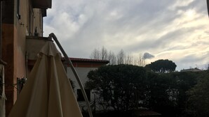 A balcony with a telescope, a building with a red-tiled roof, and a cloudy sky. - La Maison dei Miracoli (Pisa)