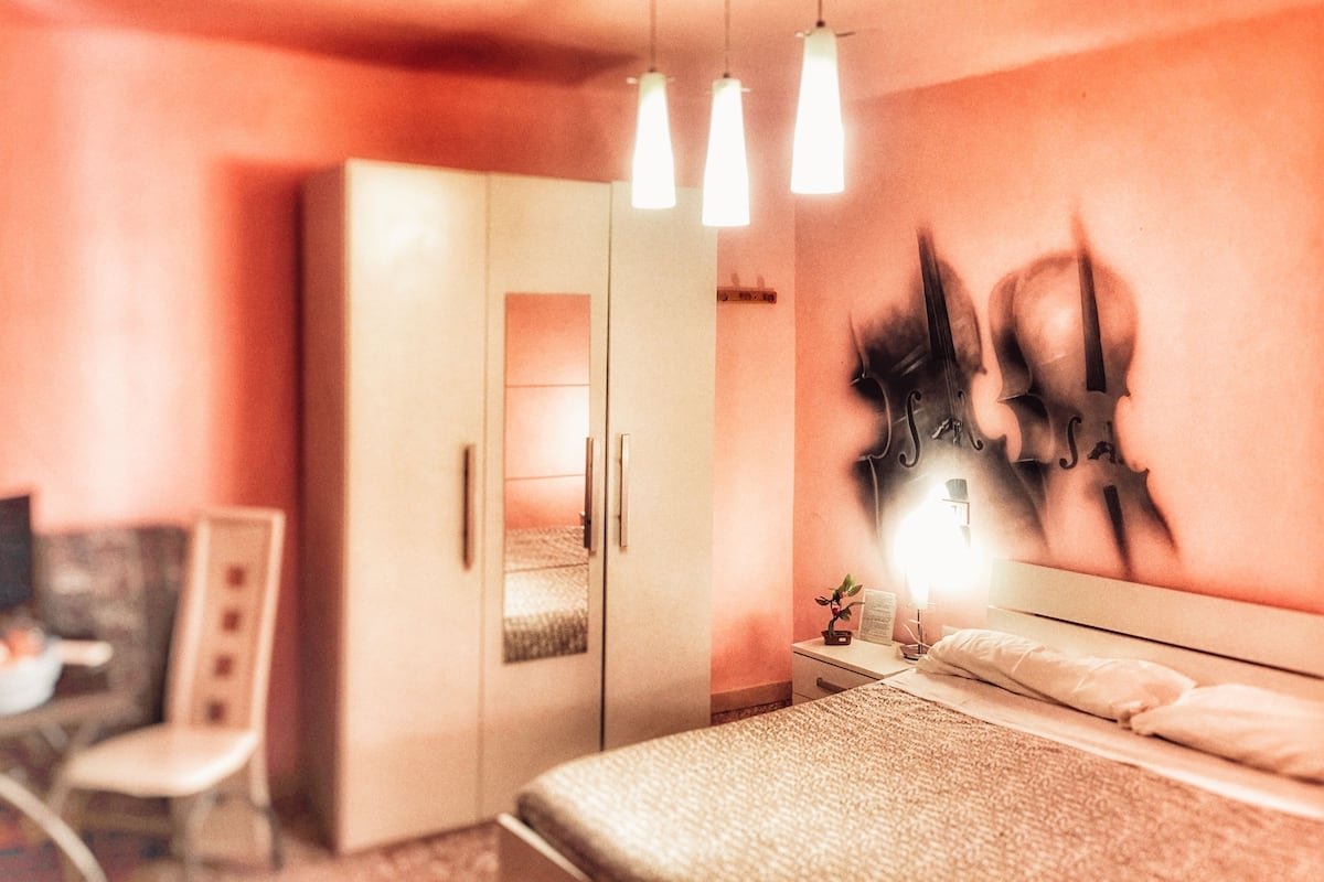 A bedroom with a bed, a wardrobe, a desk, and a chair.