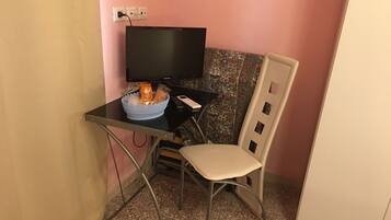 A small room with a desk, chair, and a television.