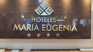 A reception desk with a sign for "HOTELES MARIA EUGENIA" and a logo above the name. - Hotel Maria Eugenia Tuxtla Gutierrez (Tuxtla Gutierrez)