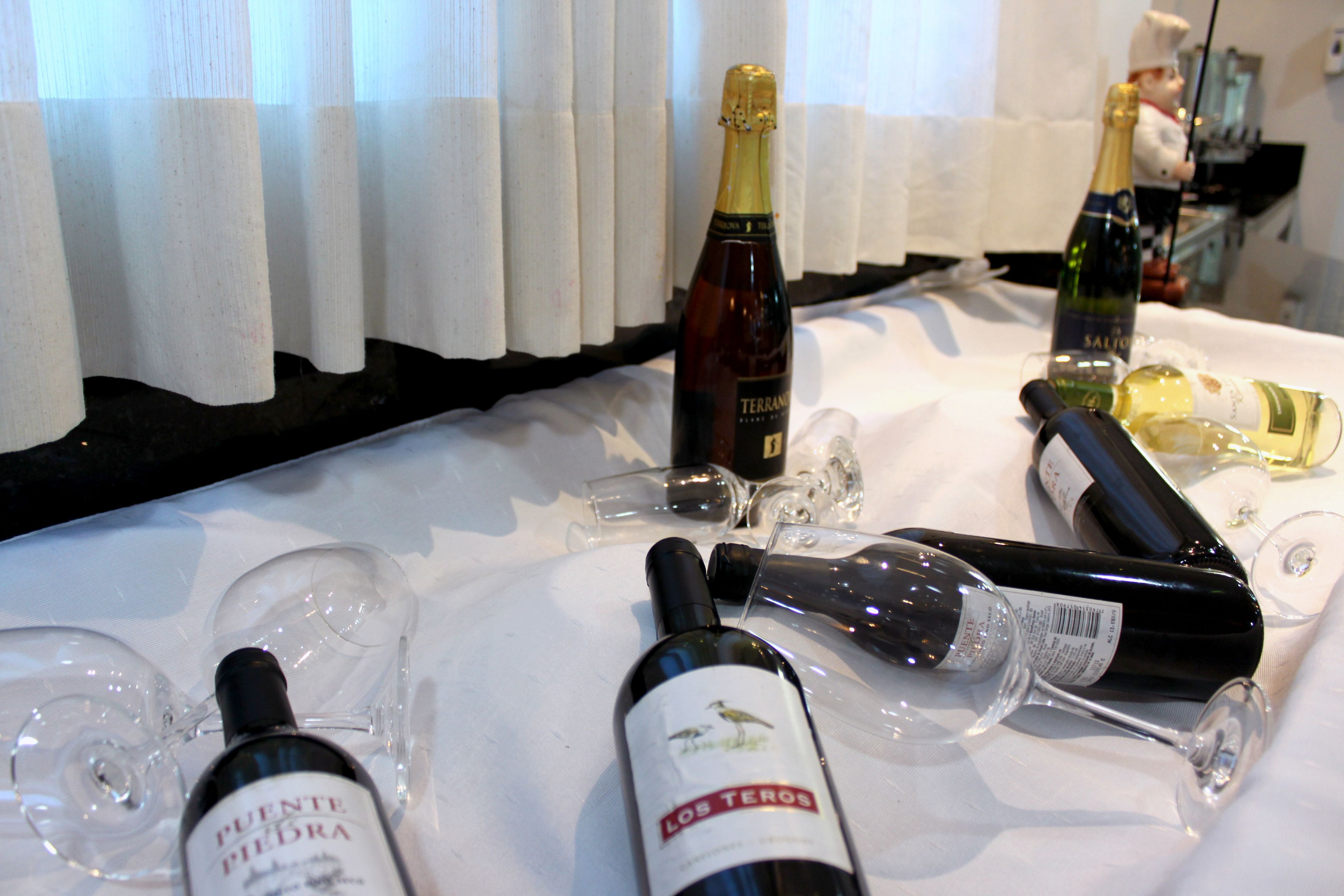 Una mesa con botellas de vino y copas, algunas de ellas vacías.