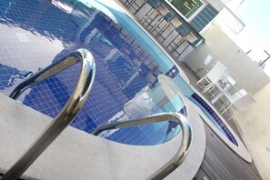 A swimming pool with a tiled floor and metal handrails. - Hotel Anahi (Jaboatão dos Guararapes)