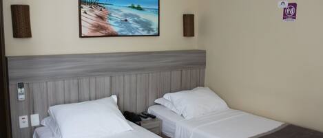 Quarto de hotel com duas camas, um quadro de uma paisagem de praia e um aviso indicando área para fumantes.