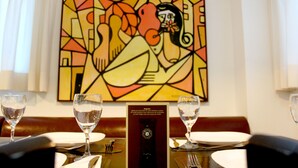 A dining table with two wine glasses, a menu, and a framed artwork on the wall. - Hotel Anahi (Jaboatão dos Guararapes)