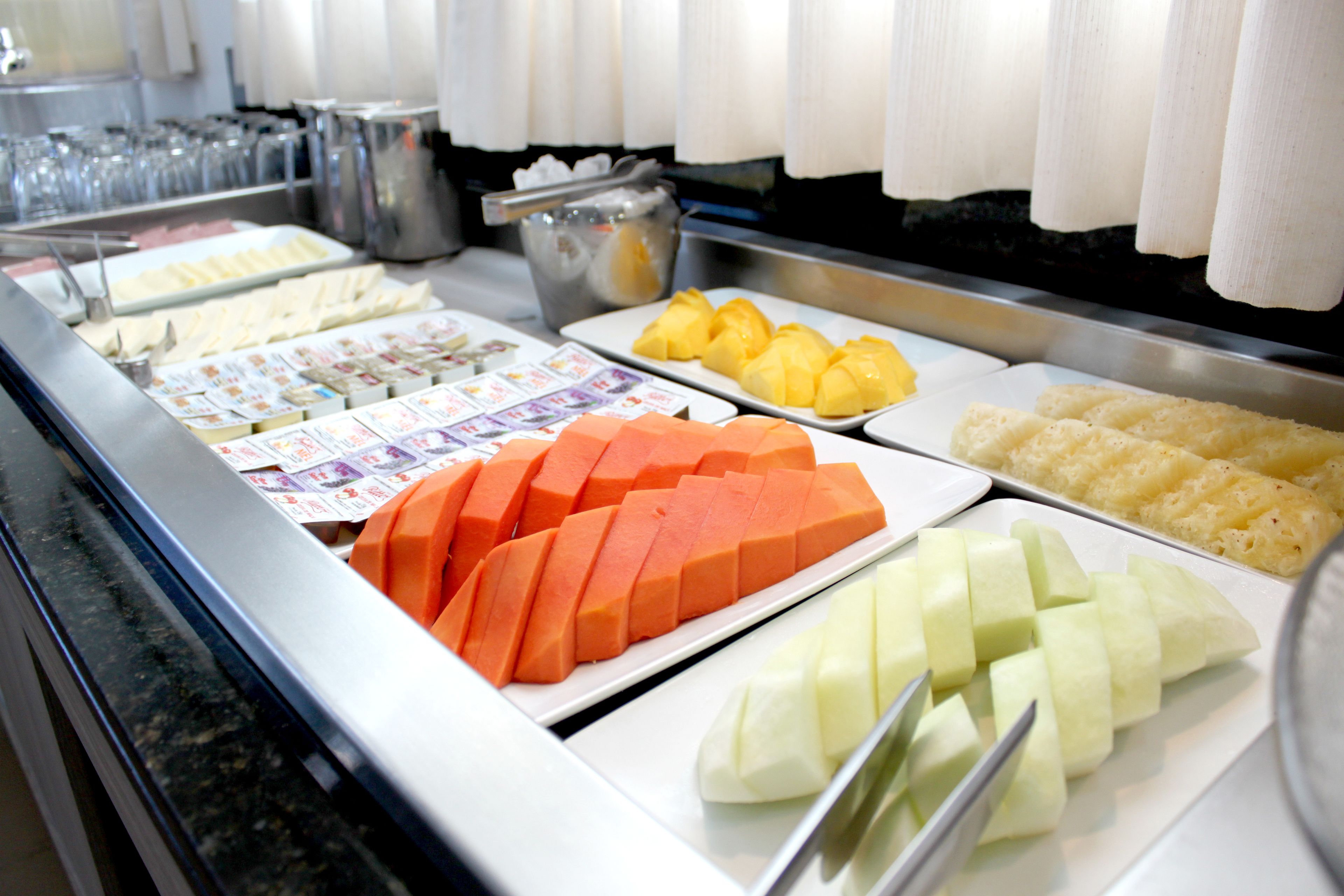 A buffet with various food items including orange and green fruit.