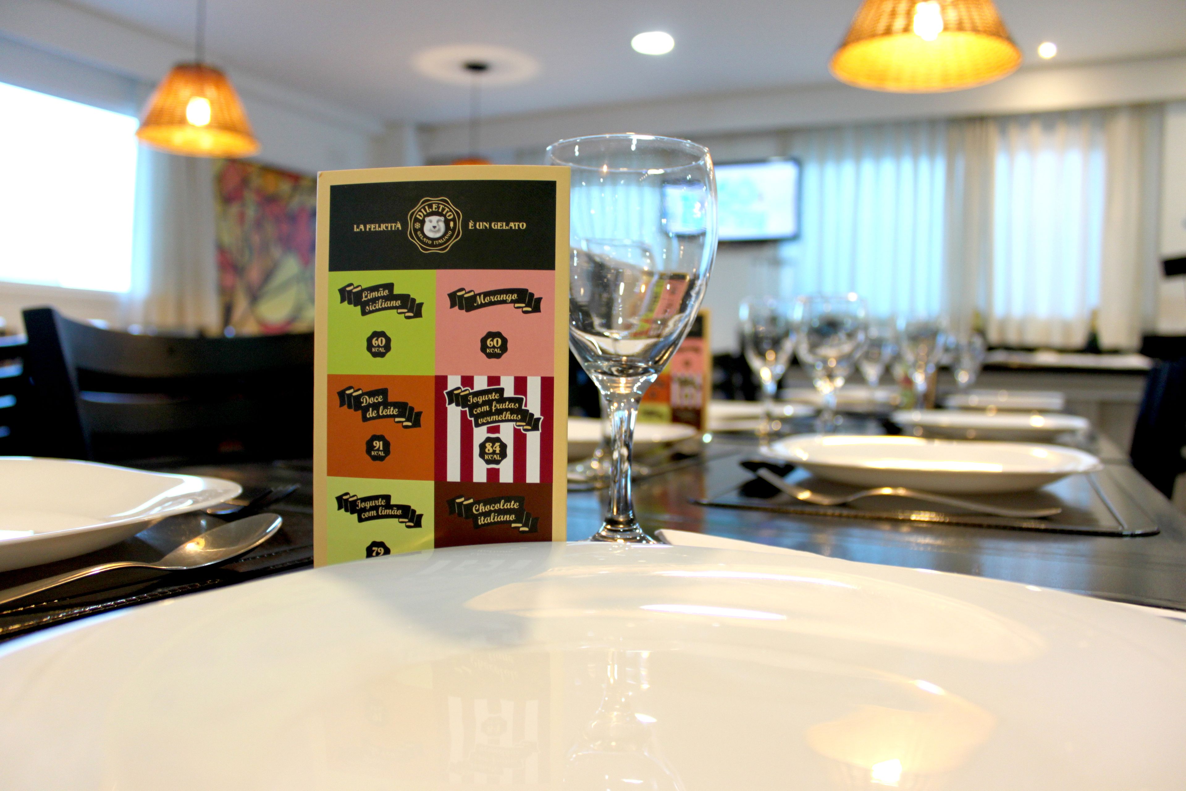 A restaurant setting with a menu board, a glass of water, and neatly arranged plates and cutlery.