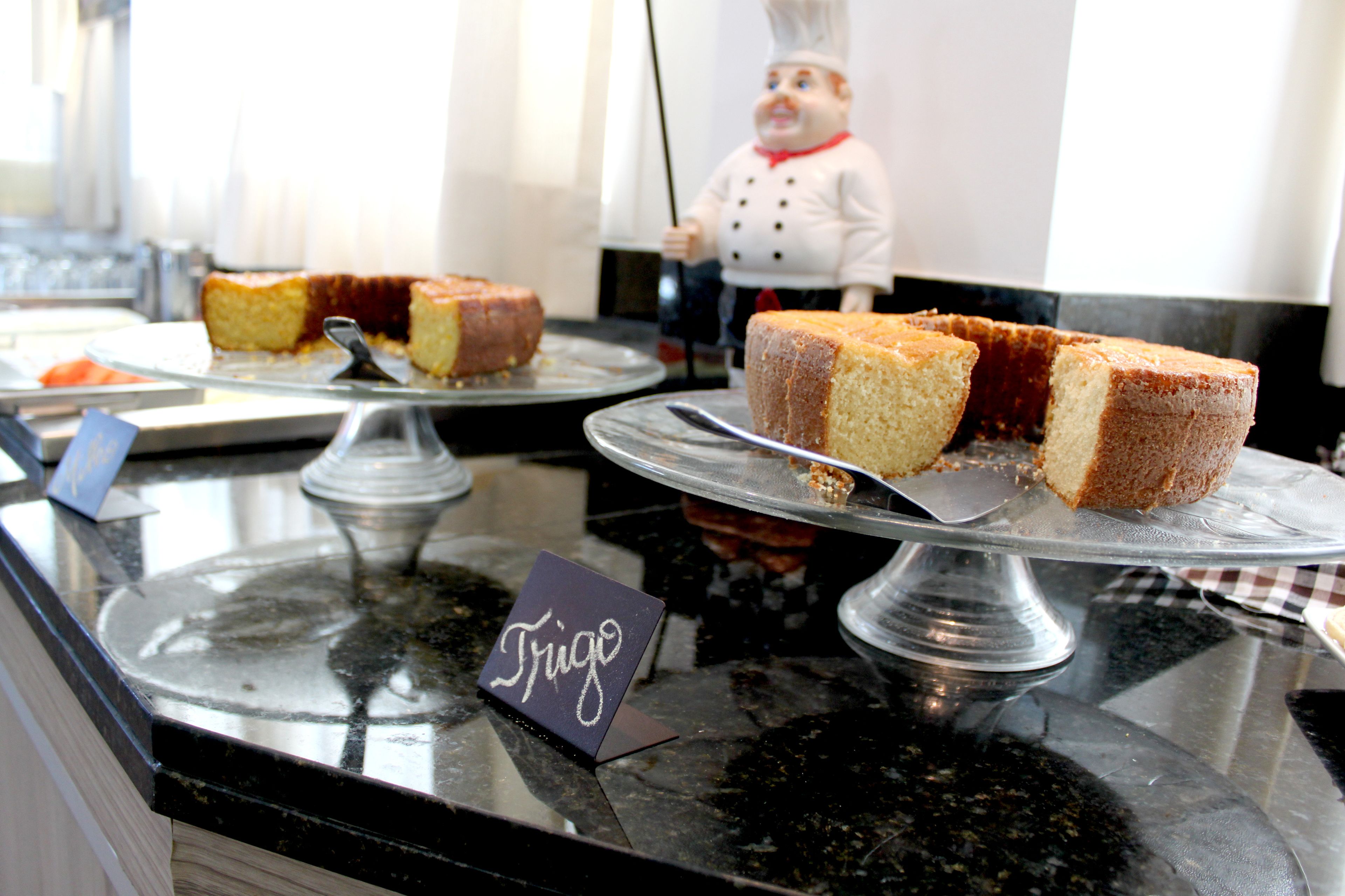 Una exhibición de postres con un letrero que dice "Frigo" y una figurita de chef al fondo.