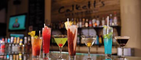 A bar with various cocktails and a wooden wall with the text "Calkett's".