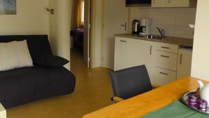 A compact living space with a sofa, a dining table, and a kitchen area.