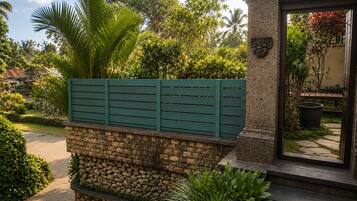 A stone wall with a green fence and a stone pillar with a plaque.