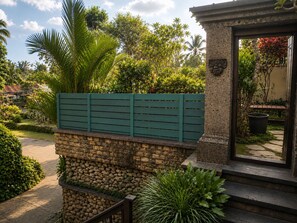 A stone wall with a green fence and a stone pillar with a plaque. - Segening Villa (Ubud)