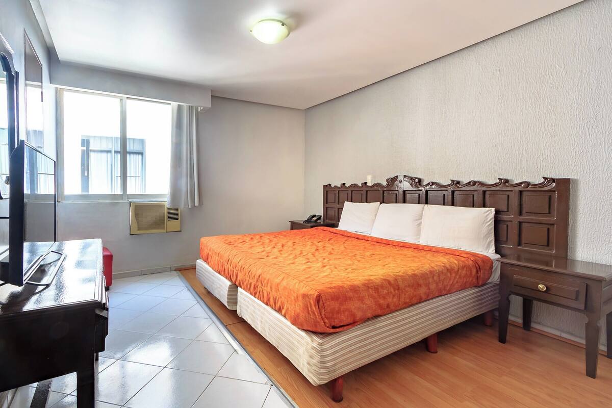 A bedroom with a bed, a desk, and a nightstand.