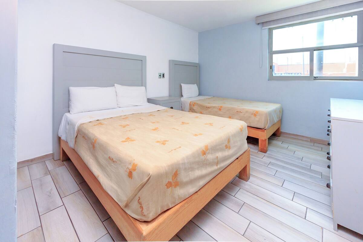 A room with two beds, a small desk, and a window.