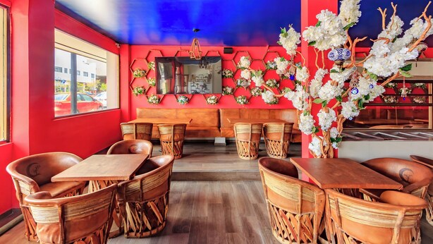 A restaurant with wooden furniture, a red wall, and a decorative white floral arrangement. - Capital O Hotel Colón Express Guadalajara (Guadalajara)