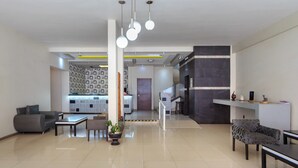 A spacious living area with a sofa, armchairs, a coffee table, and a potted plant. - Capital O Hotel Colón Express Guadalajara (Guadalajara)
