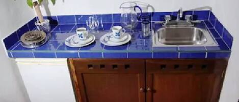 A compact kitchen with blue tiles, a sink, and cabinets.