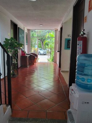 A hallway with tiled flooring, a reception desk, a water dispenser, and a fire extinguisher.