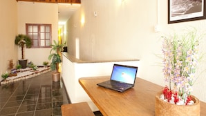 A wooden table with a laptop, a potted plant with flowers, and a framed picture on the wall. - HMG Praia Suites for Rent (Rio de Janeiro)
