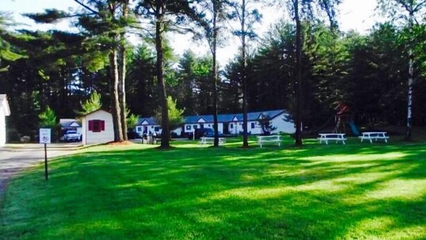 A campground with RVs, picnic tables, and a small cabin. - Saco River Motor Lodge & Suites (Center Conway)