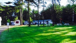A campground with RVs, picnic tables, and a small cabin. - Saco River Motor Lodge & Suites (Center Conway)