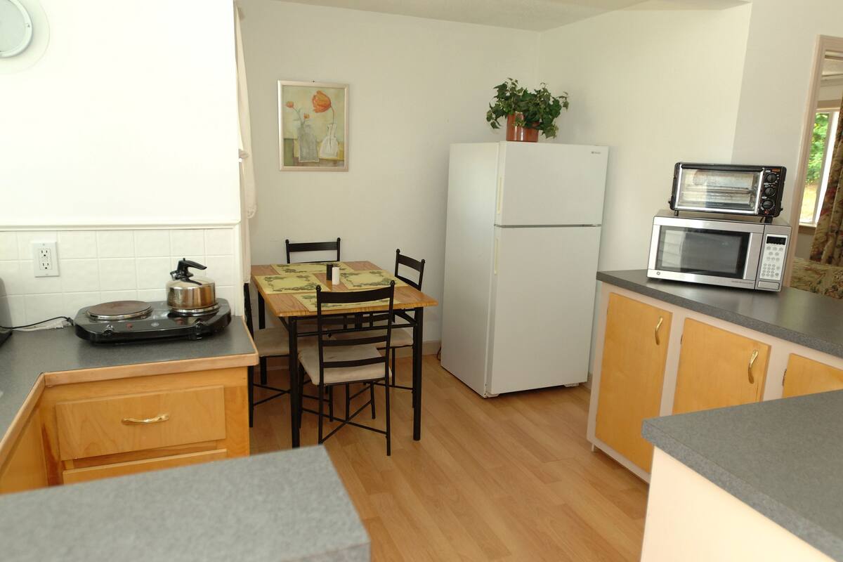 A compact kitchen with a dining table, chairs, a refrigerator, a microwave, and a small countertop.
