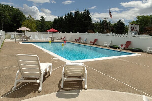 A swimming pool with lounge chairs and a sign indicating the location. - Saco River Motor Lodge & Suites (Center Conway)