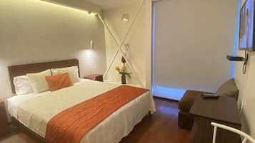 A hotel room with a bed, a desk, a chair, and a window.