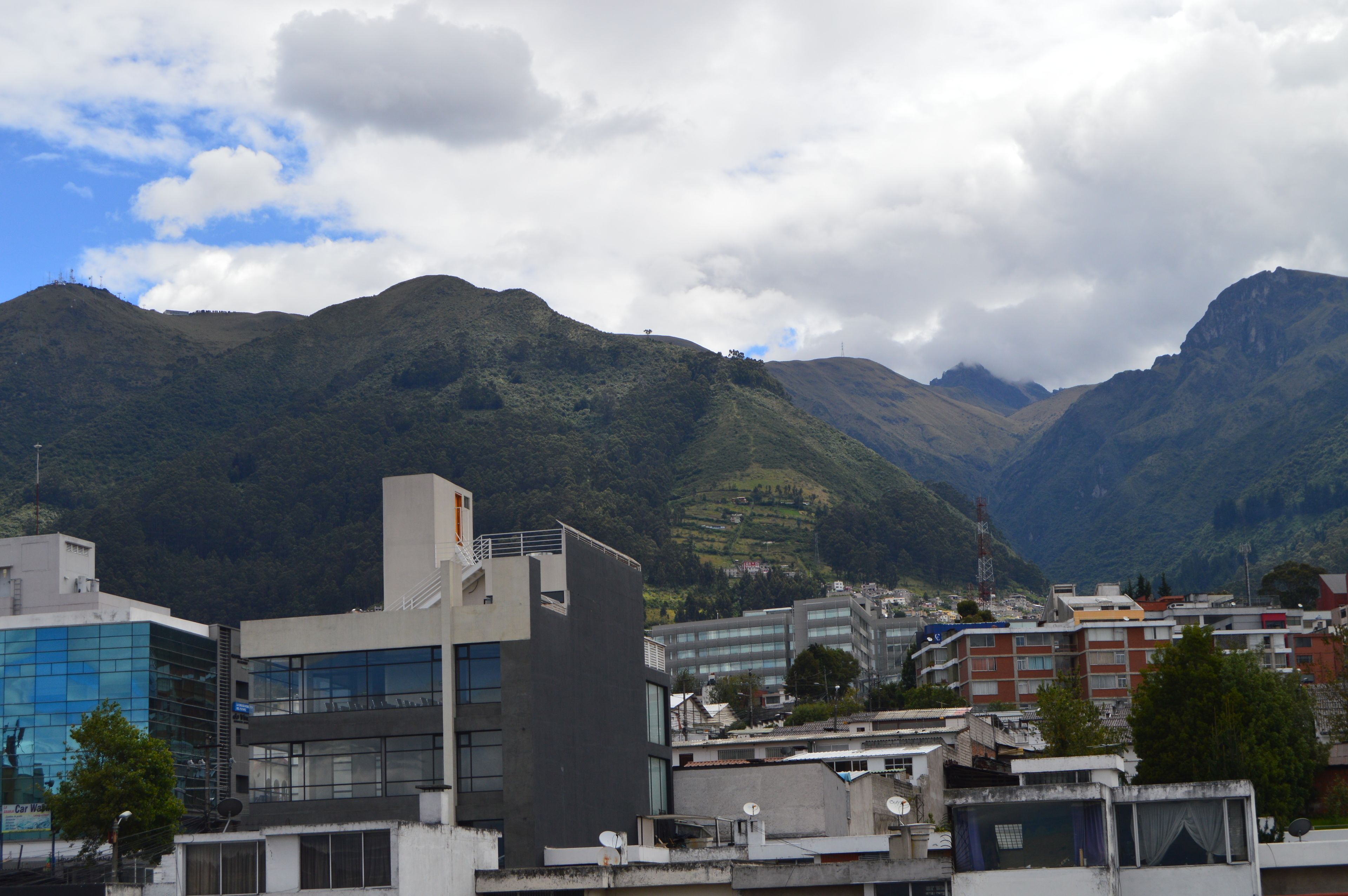 A cityscape with modern buildings and a mountainous backdrop.